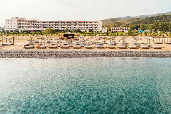 Strand med solsenger og parasoller foran et hotell. (AI-generert tekst)