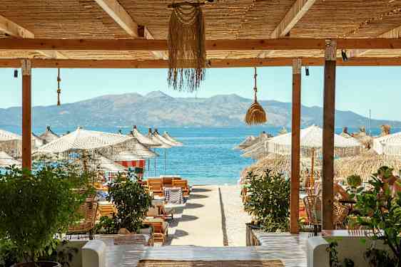 Strandutsikt med parasoller, solsenger og havet i bakgrunnen. (AI-generert tekst)