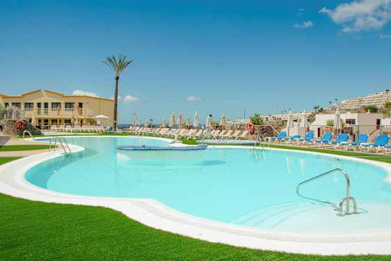 Et basseng ved et hotell omgitt av solsenger og parasoller. (AI-generert tekst)