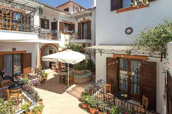 Indre gårdsplass med kaféområde og blomsterpotter. (AI-generert tekst)