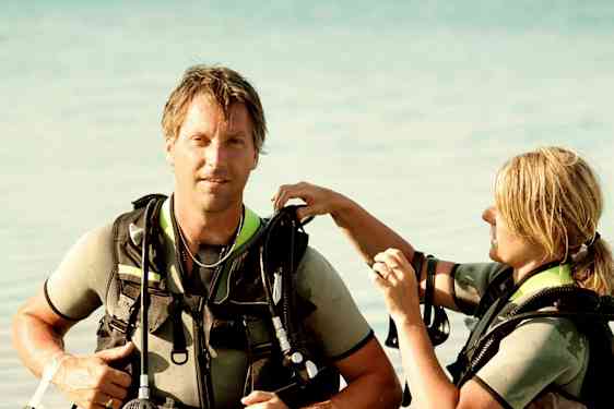 To personer i dykkerutstyr står i grunt vann. (AI-generert tekst)