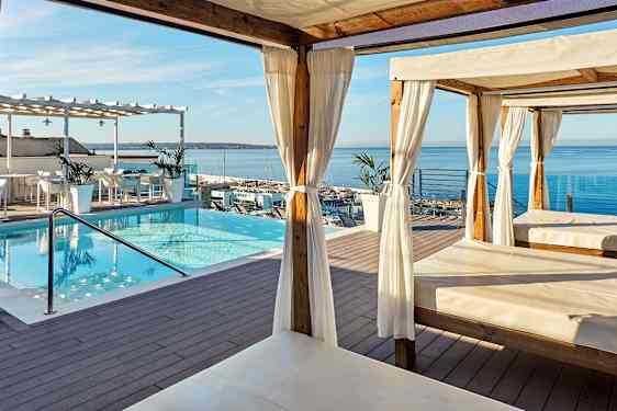 Terrasse med basseng, cabanas og utsikt over havet. (AI-generert tekst)