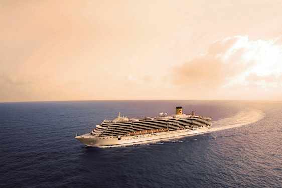 Et cruiseskip seiler på havet under en varm oransje himmel. (AI-generert tekst)