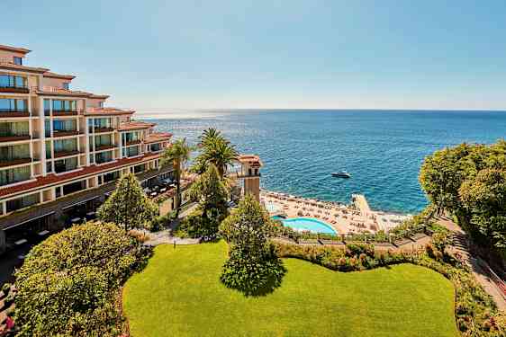 Bilde av et hotell ved kysten, med havutsikt, bassengområde og solsenger. (AI-generert tekst)