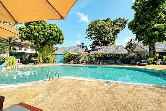 Utendørsbasseng med solsenger og en lekeplass i bakgrunnen. (AI-generert tekst)