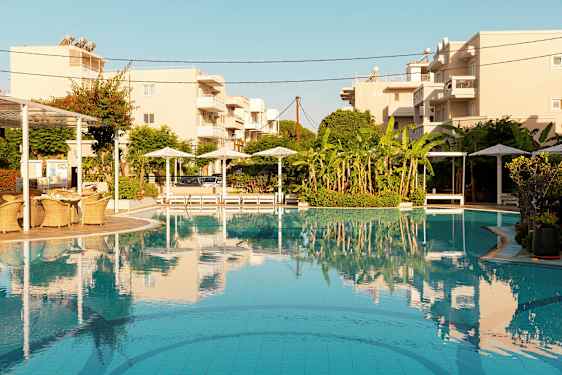 Bassengområde med parasoller, solsenger og bygninger i bakgrunnen. (AI-generert tekst)