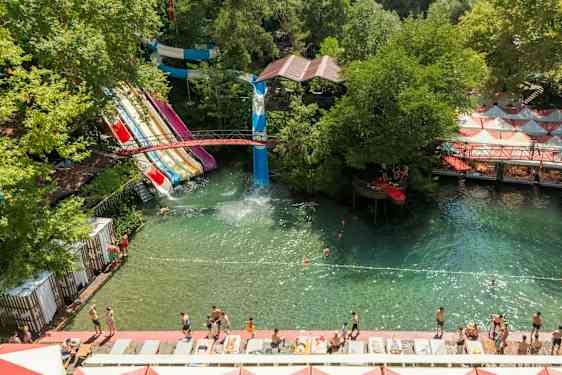 Vannpark med flere vannsklier og badeområde omgitt av grøntområder. (AI-generert tekst)