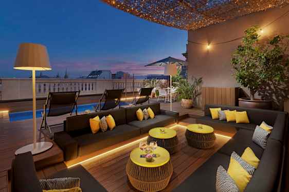 En terrasse med moderne møbler, et basseng og belysning ved solnedgang. (AI-generert tekst)