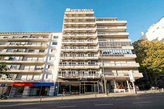 Leilighetsbygg med hotelskilt og balkonger under en klar blå himmel. (AI-generert tekst)