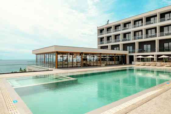 Et hotell med moderne bassengområde og havutsikt. (AI-generert tekst)