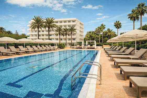 Et hotellbasseng omgitt av solsenger og parasoller med en bygning i bakgrunnen. (AI-generert tekst)