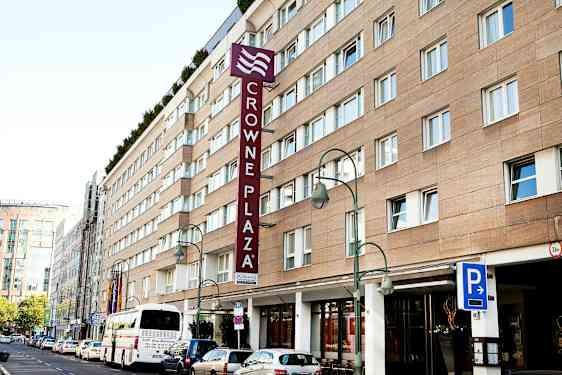 Crowne Plaza-hotellet bygning med parkeringsskilt og buss foran. (AI-generert tekst)