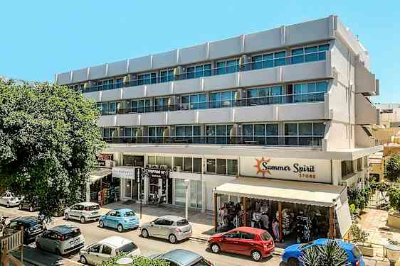 En fleretasjes bygning med butikk og biler parkert foran. (AI-generert tekst)