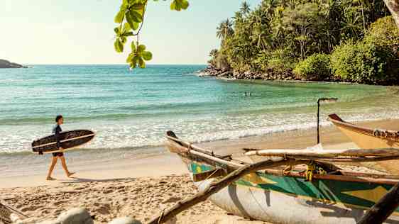 Surfare på en strand på Sri Lanka