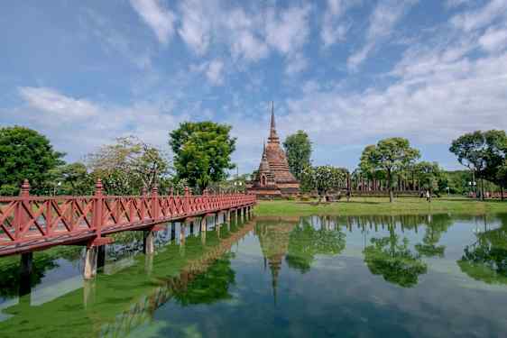 Bro över vatten till tempel i Sukhothai Historical Park