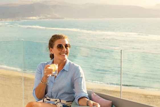 Kvinne koser seg med en drink på balkongen på Gran Canaria