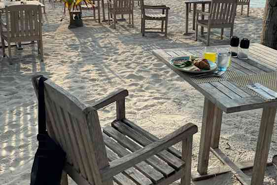 Bord og stoler på stranden i morgensol