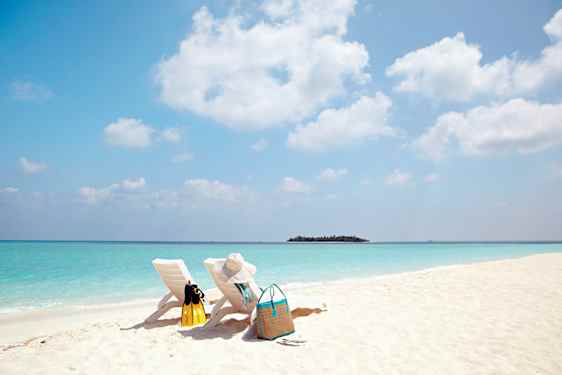 To solsenger på stranden med utsikt over turkist hav på Maldivene