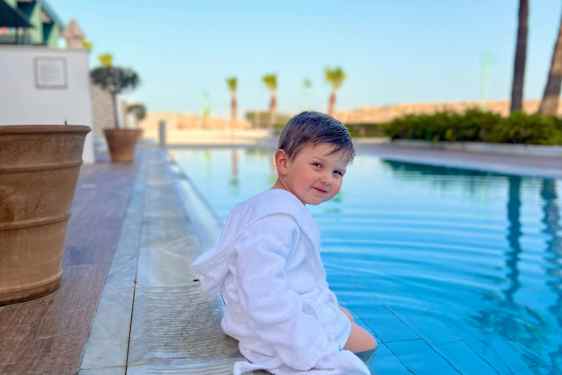 Barn sitter ved bassenget.