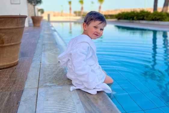 Barn sitter ved bassenget.