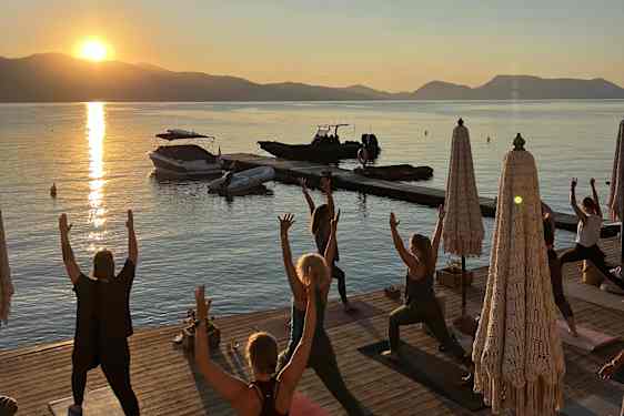 Yogatrening i soloppgang på brygge ved havet
