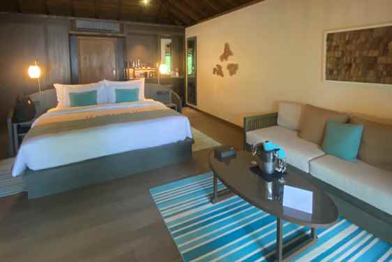 Villa sett fra innsiden, med stor seng, loungegruppe og detaljer i turkise toner