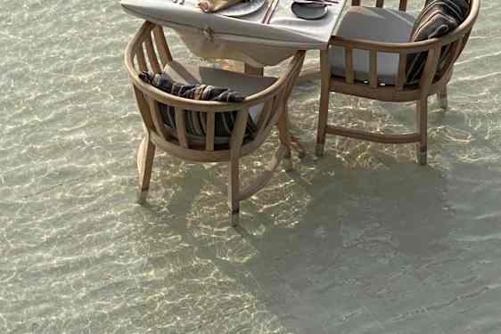 Dekket bord med to stoler stående i havet