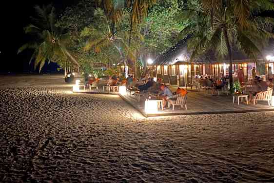 Opplyst strandrestaurant blandt palmer