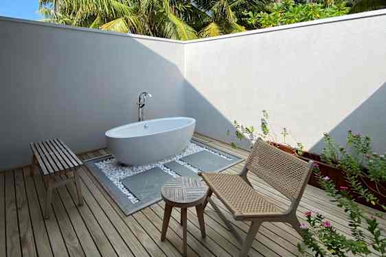 Utendørs bad med badekar, loungegruppe og palmer