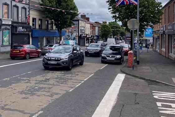 Gate med biler og Storbritanniens flag på en lyktstolpe.