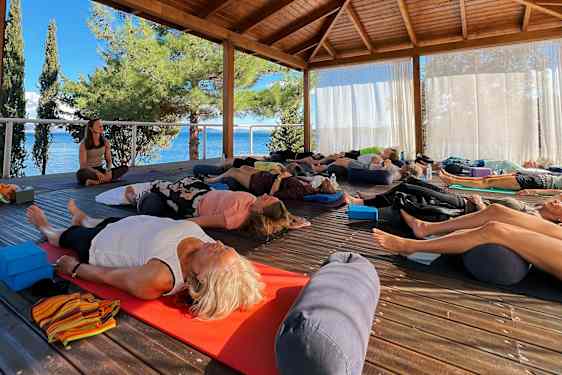 Gruppe som trener yoga og som ligger på matte og gjør pusteøvelser