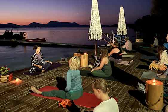 Grytidlig morgen med yoga på brygga, gruppen sitter ved havet.