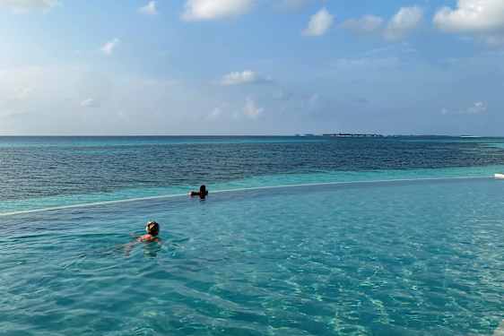 To personer svømmer i infinitypool ut mot havet