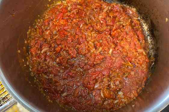 Løk og tomat i en gryte.