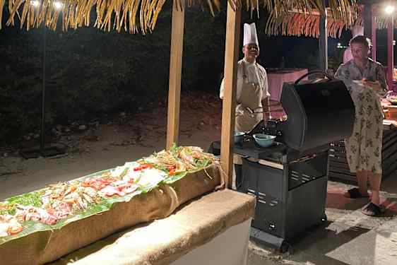 Kokk ved grillen på stranden om kvelden