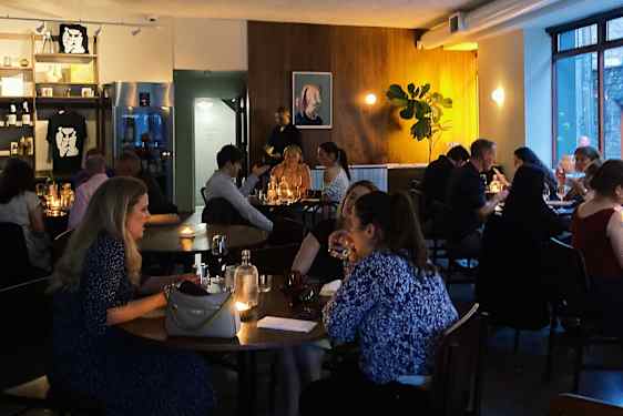 Folk sitter ved bord på en restaurang med dempet belysning