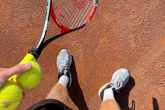 Mann holder en tennisracket og ball