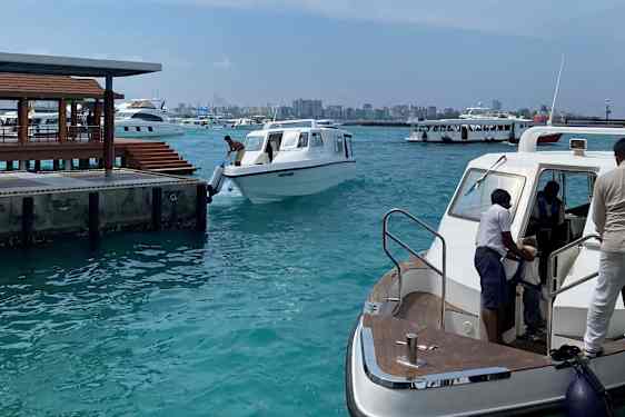 Havn med flere speedbåter, med Malés silhuett i bakgrunnen