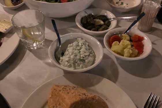 Et måltid med ulike småretter, salat, oliven og nybakt brød er servert på et restaurantbord. De mange skålene inviterer til et sosialt måltid med deling.