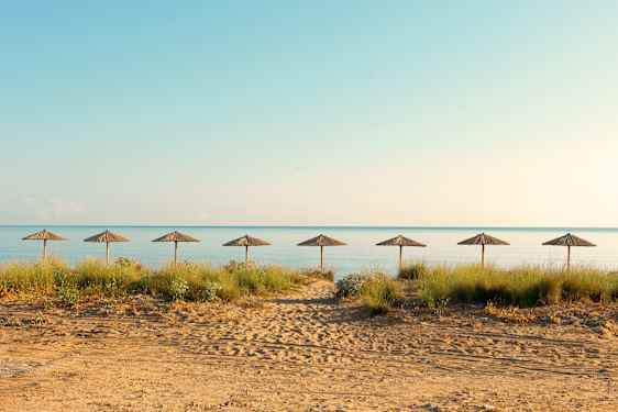 Strand med parasoller og rolig hav i bakgrunnen