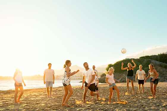 Familie spiller fotball på stranden