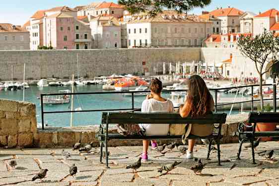 To kvinner sitter på en benk og ser mot Dubrovniks gamleby