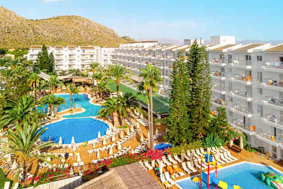 Översiktsbild på VIVA Sunrise, Mallorca. Poolområde och restaurang omgivet av palmer och hotellbyggnader.
