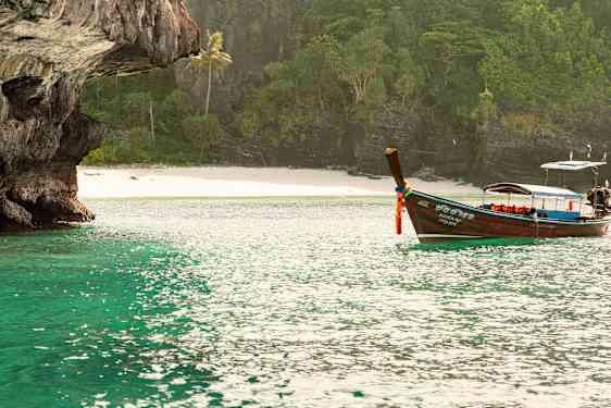 Longtailbåt på vannet utenfor den frodige øya Koh Phi Phi