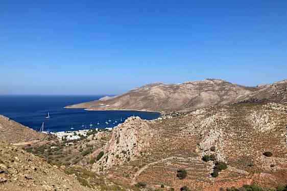 Landskapsbilde av Tilos' fjellkjede og en liten vik med blått vann.
