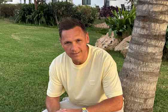 Joakim Hykkerud lener seg inntil en palme