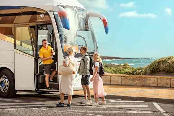 Tre personer møter en guide ved en transferbuss