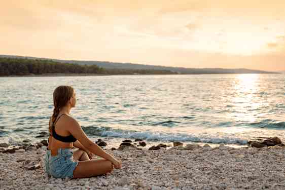 En ung kvinne nyter solnedgangen på en strand i Kroatia