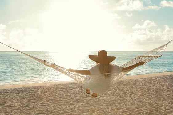 Kvinde sidder i en hængekøje og ser ud over vandet