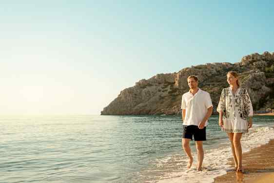 Ett par går på en strand i solnedgången